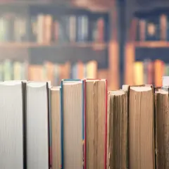 Rząd książek w zbliżeniu na tle biblioteki.