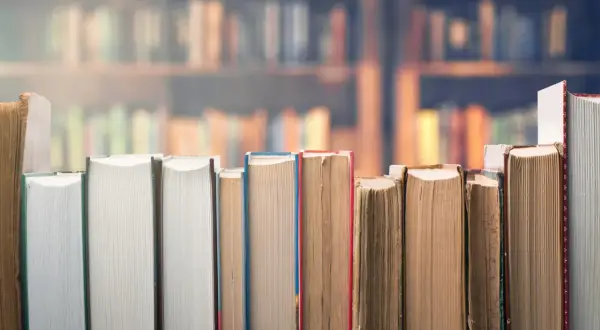 Rząd książek w zbliżeniu na tle biblioteki.